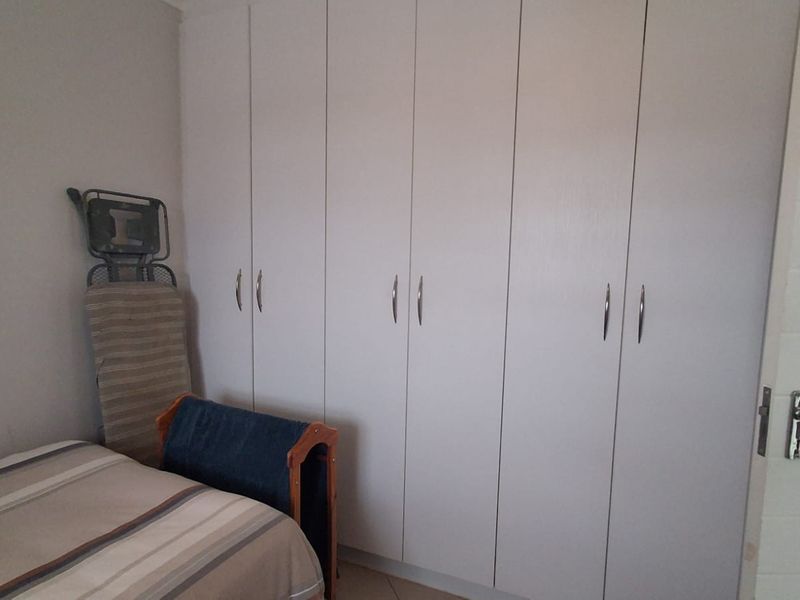 A bedroom featuring floor-to-ceiling built-in cupboards with white doors and modern handles.