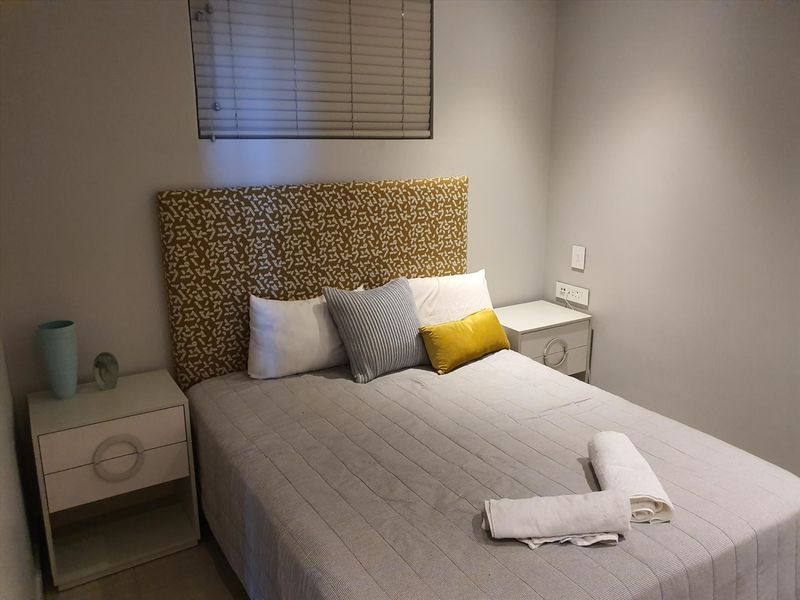 A well-maintained bedroom featuring neutral walls, a window with venetian blinds, and integrated electrical fixtures.
