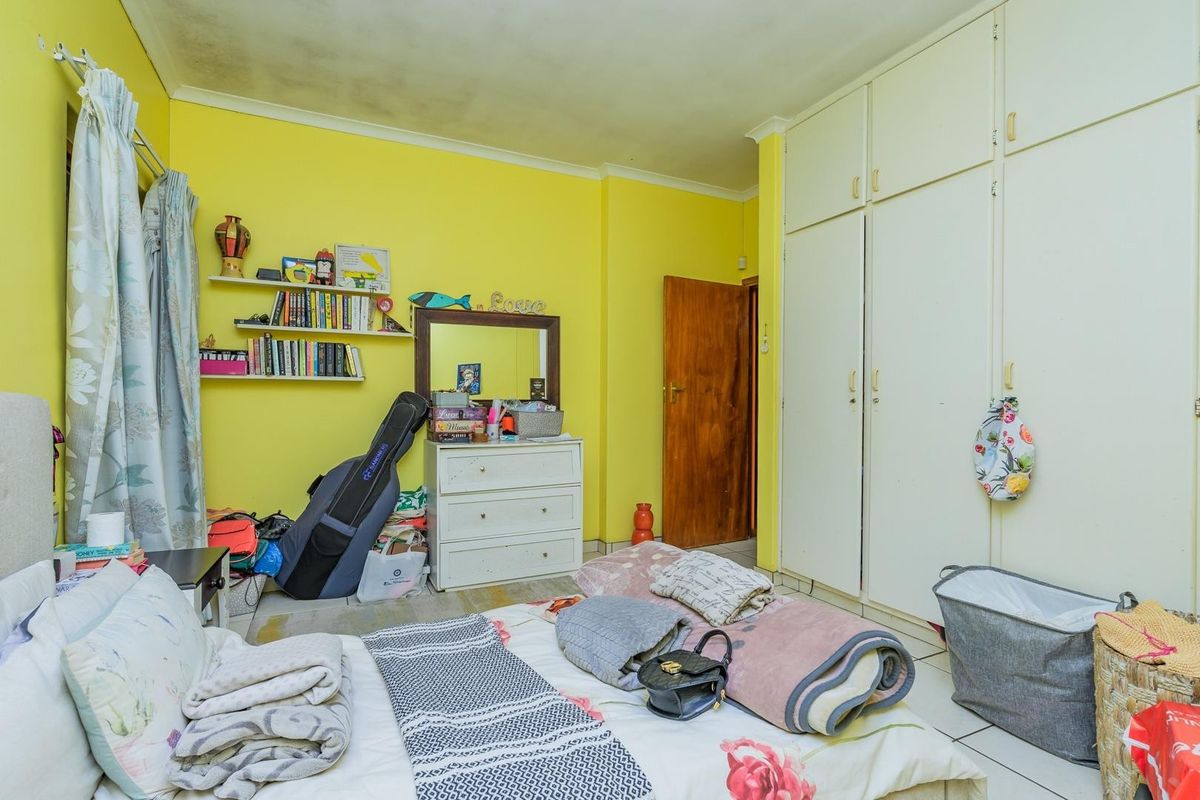 A bedroom featuring built-in cupboards, tiled flooring, and a timber door, requiring cosmetic updates to the walls and ceiling.
