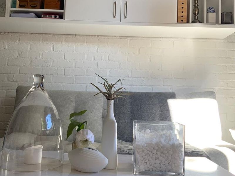 A cozy living area featuring a painted brick wall and integrated white wall-mounted cabinetry for storage.