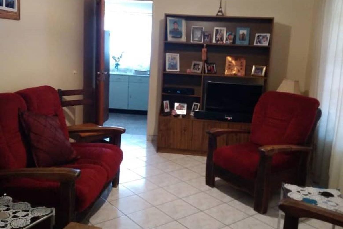 A living room featuring tiled flooring with a view into an adjacent kitchen area.
