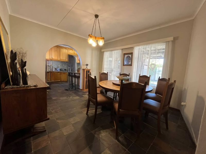 Dining room featuring slate tile flooring, an arched entryway leading to the kitchen, and sliding glass doors providing natural light.