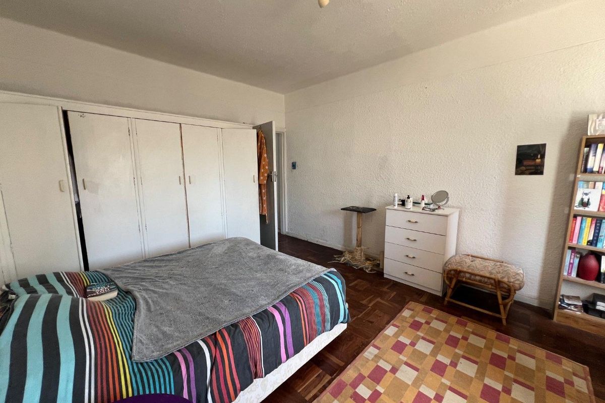Bedroom featuring original parquet flooring and a large built-in wardrobe, offering a functional space with potential for cosmetic updates.