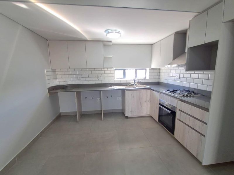 Modern kitchen featuring light wood-grain cabinetry, stone countertops, subway tile backsplash, and integrated stainless steel appliances including a gas hob and oven.