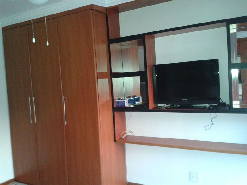 Bedroom featuring a large built-in wooden wardrobe and a matching integrated shelving unit with display space.