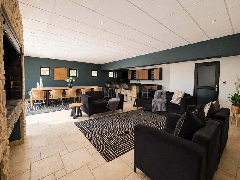 Spacious open-plan living and dining area featuring a stone fireplace, built-in bar, and neutral tiled flooring with recessed lighting.