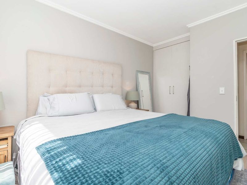 A well-maintained bedroom featuring neutral wall tones, built-in cupboards, and crown molding, providing a clean and comfortable living space.
