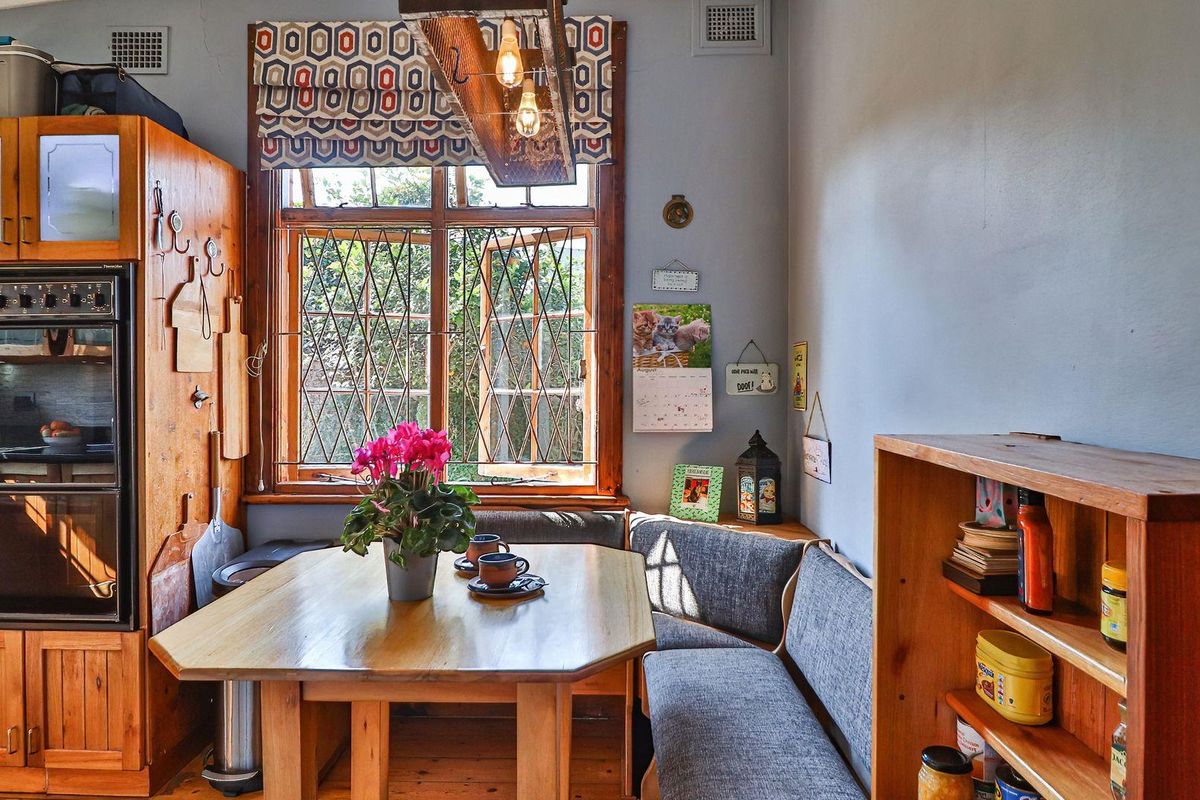A cozy kitchen area featuring timber cabinetry, a built-in oven, and a charming window with leaded glass detailing.