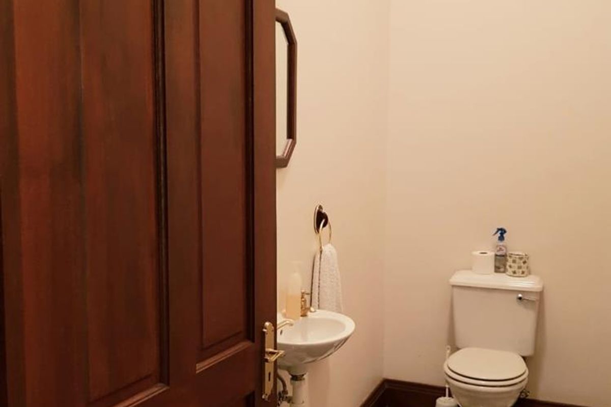 A compact powder room featuring a wall-mounted basin, a standard toilet, and classic black and white checkered floor tiling.