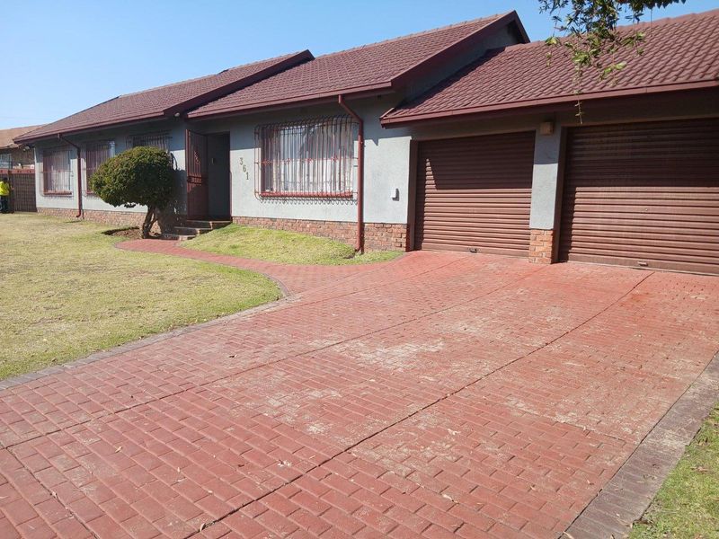 Front elevation of a single-story house featuring a double garage, brick paved driveway, and tiled roof with security bars on windows.