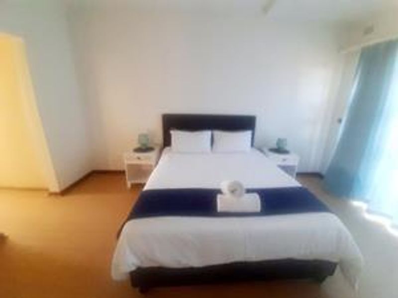 A simple bedroom featuring carpeted flooring and natural light from the window area.
