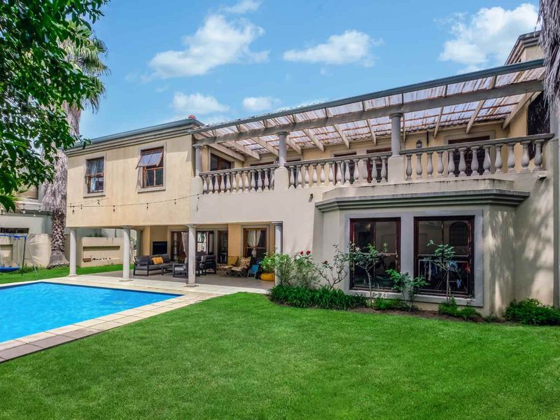 Rear view of a two-story house featuring a swimming pool, a covered ground-floor patio, and an upper-level balcony with a balustrade.
