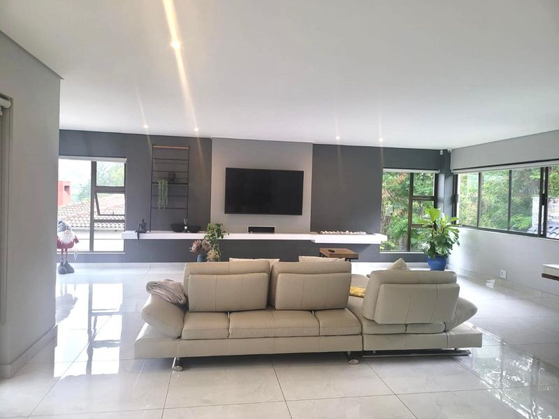 Spacious living room featuring large windows, polished tiled flooring, recessed lighting, and a modern built-in media console wall.