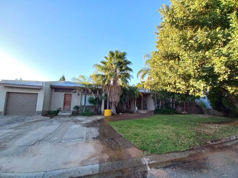 Front exterior view of the house featuring a paved driveway, attached garage, and established garden area.