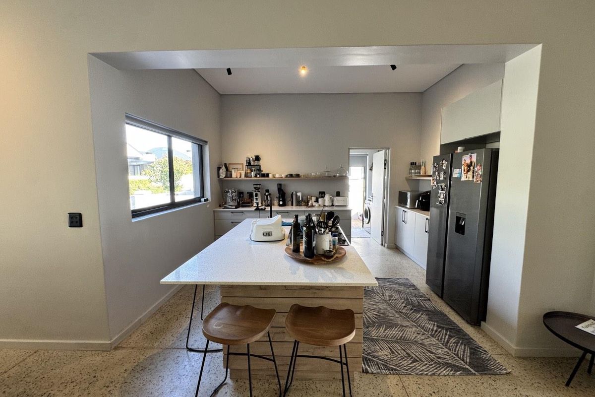 Modern kitchen featuring a central island with stone countertops, terrazzo flooring, and clean cabinetry, offering a bright and functional culinary space.