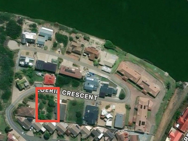 An aerial view of a residential vacant land plot located within a suburban neighborhood, highlighting its position and surrounding context.