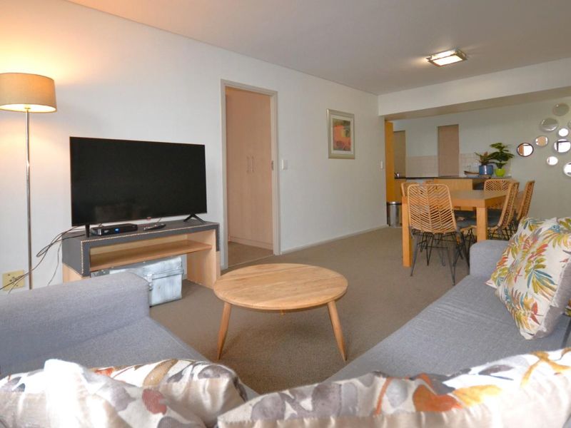 Open plan living and dining area featuring neutral carpeting and a functional kitchen layout with built-in cabinetry.