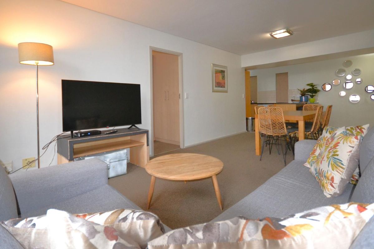 Open plan living and dining area featuring neutral carpeting and a functional kitchen layout with built-in cabinetry.