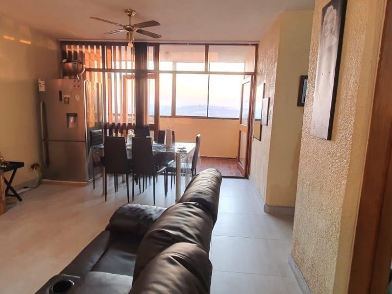Open-plan living and dining area featuring tiled floors, a ceiling fan, and direct access to a balcony with natural light.