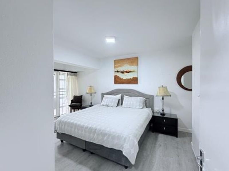 A well-maintained bedroom featuring light-toned laminate flooring and a sliding glass door providing access to an outdoor area.