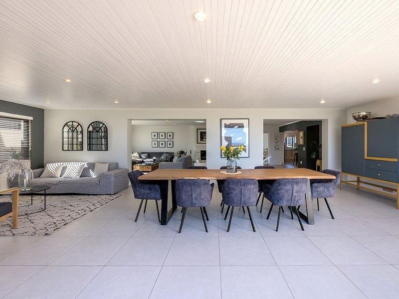 Spacious open-plan living and dining area featuring modern tiled flooring, recessed downlighting, and a clean tongue and groove ceiling finish.