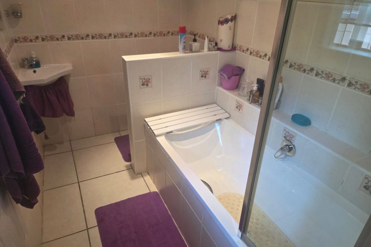 A functional bathroom featuring a built-in bathtub, corner basin, and tiled finishes throughout, offering a classic layout ready for modern updates.