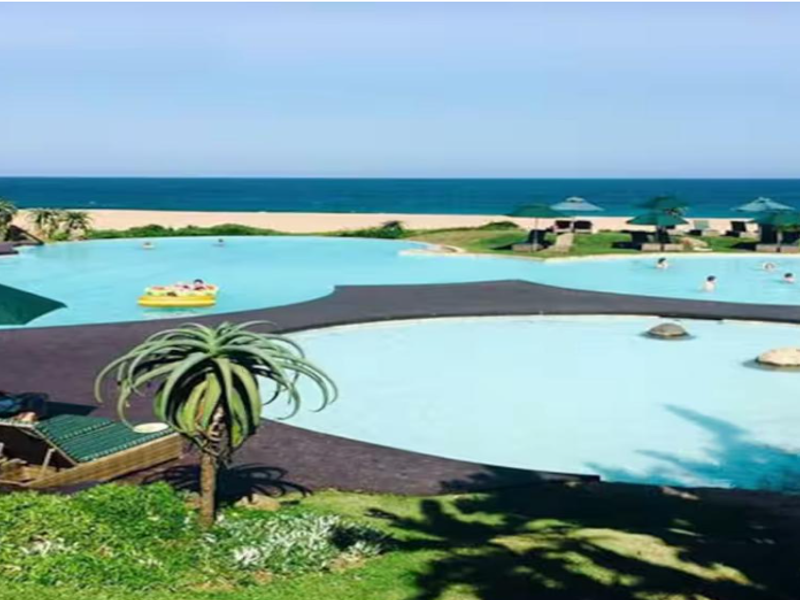 A scenic outdoor swimming pool area featuring a multi-level pool design with ocean views and landscaped surroundings.