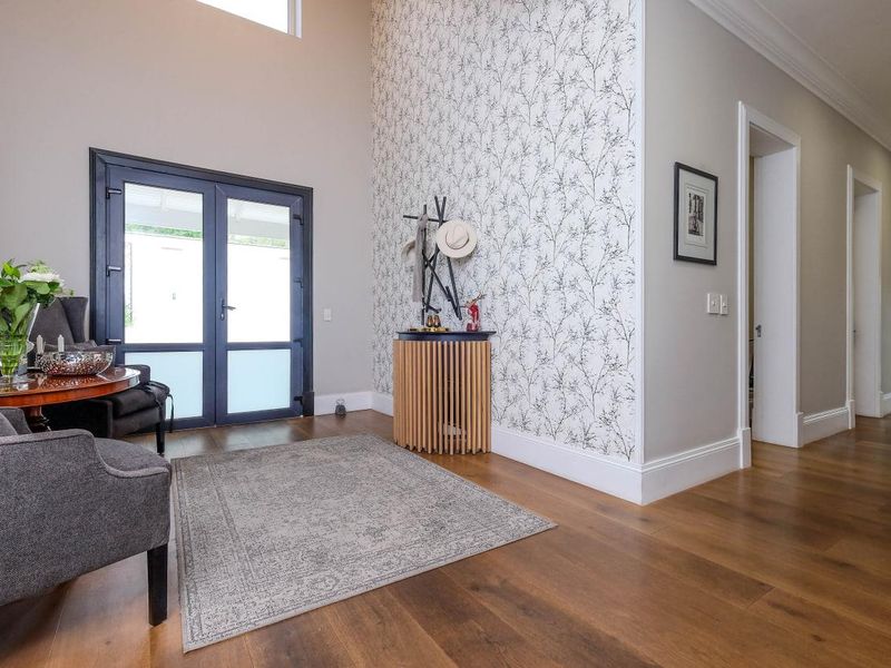 Spacious entrance hall featuring high ceilings, hardwood flooring, and a decorative feature wall, providing a bright and welcoming transition into the home.