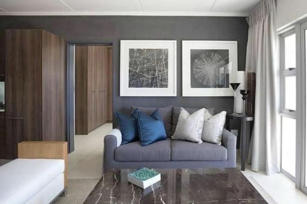 A modern living room featuring dark accent walls, tiled flooring, and a sliding glass door providing natural light.