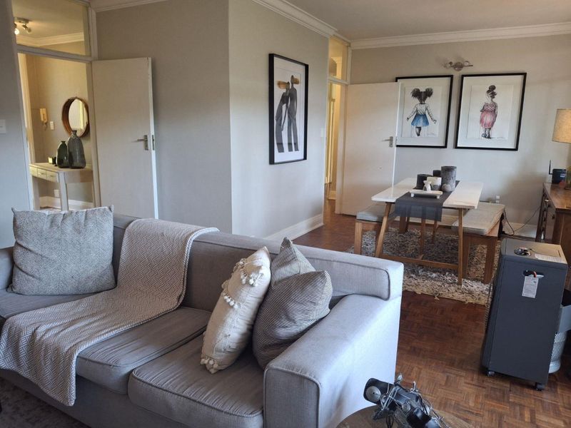 Open plan living and dining area featuring classic parquet flooring, crown molding, and neutral wall finishes with access to adjacent rooms.