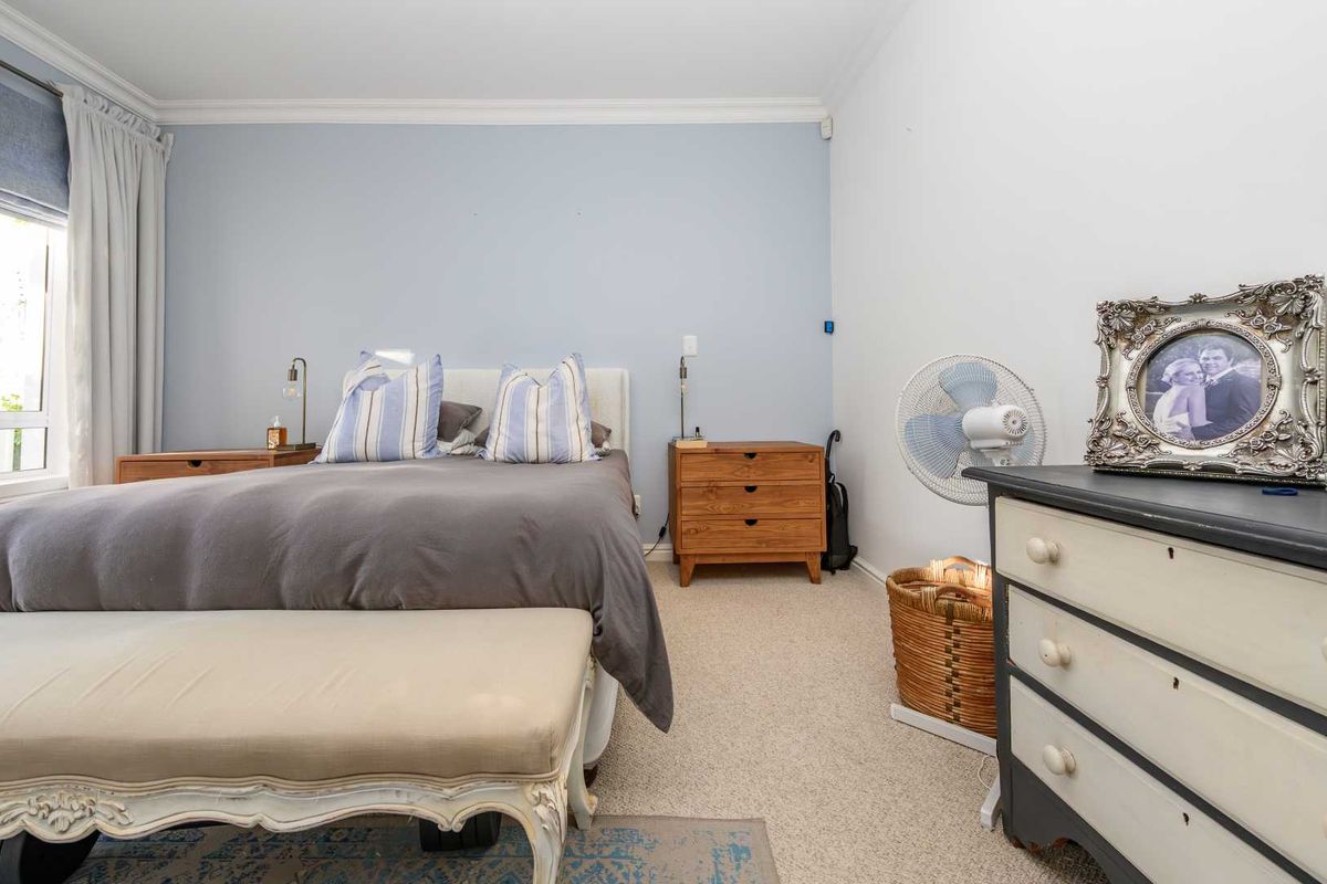 A well-lit bedroom featuring neutral carpeting, crown molding, and a soft blue accent wall, providing a comfortable and functional living space.