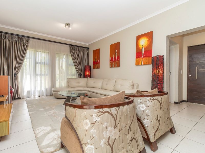 A well-maintained living room featuring tiled flooring, neutral walls, and large sliding glass doors that provide ample natural light.