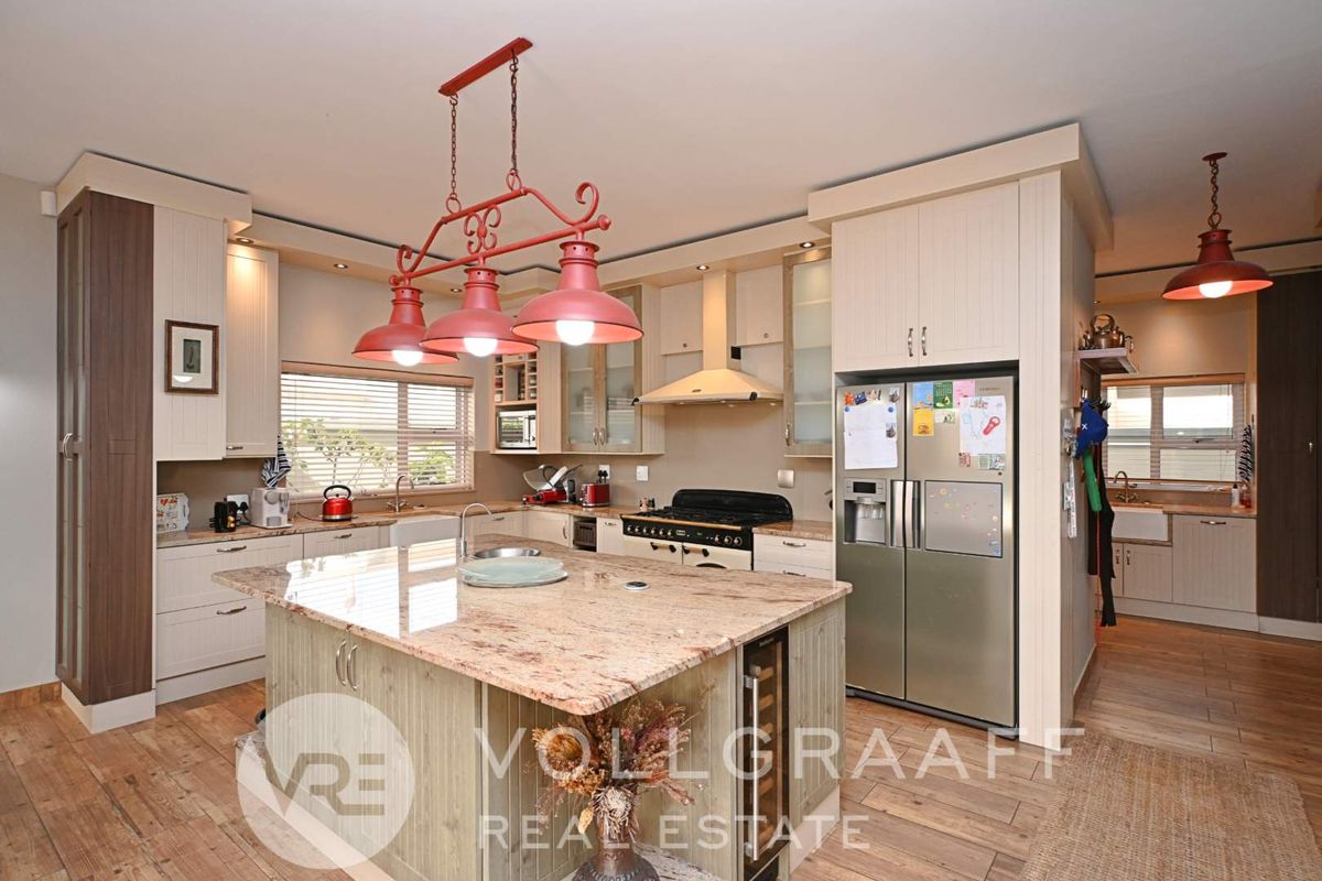 Spacious kitchen featuring a large granite-topped island, custom cabinetry, integrated wine cooler, and a secondary scullery area for additional prep and storage.