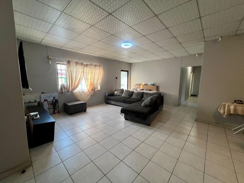 Spacious living area featuring tiled flooring and a drop ceiling, offering a functional layout ready for modernization and aesthetic updates.