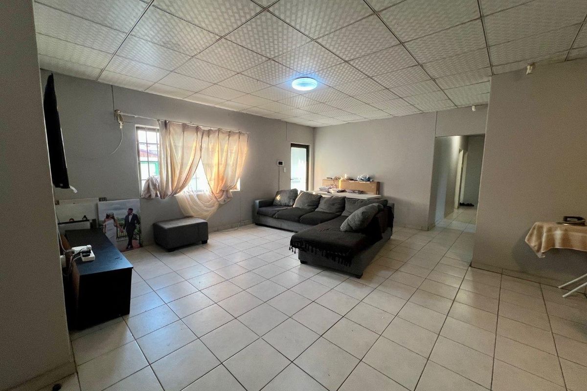 Spacious living area featuring tiled flooring and a drop ceiling, offering a functional layout ready for modernization and aesthetic updates.