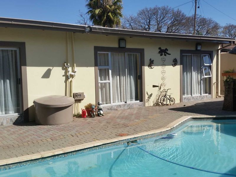 Outdoor pool area featuring a paved patio, swimming pool, and multiple sliding glass door access points to the apartment.