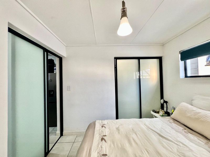 A bedroom featuring tiled flooring and built-in sliding door cupboards with frosted glass panels.
