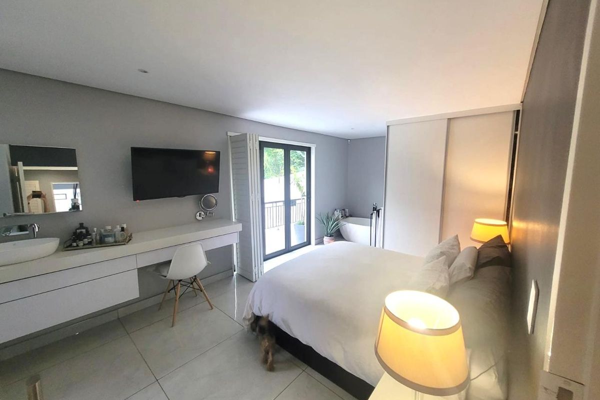 Modern bedroom featuring tiled flooring, a built-in vanity with integrated basin, sliding wardrobe, and direct access to a private balcony.