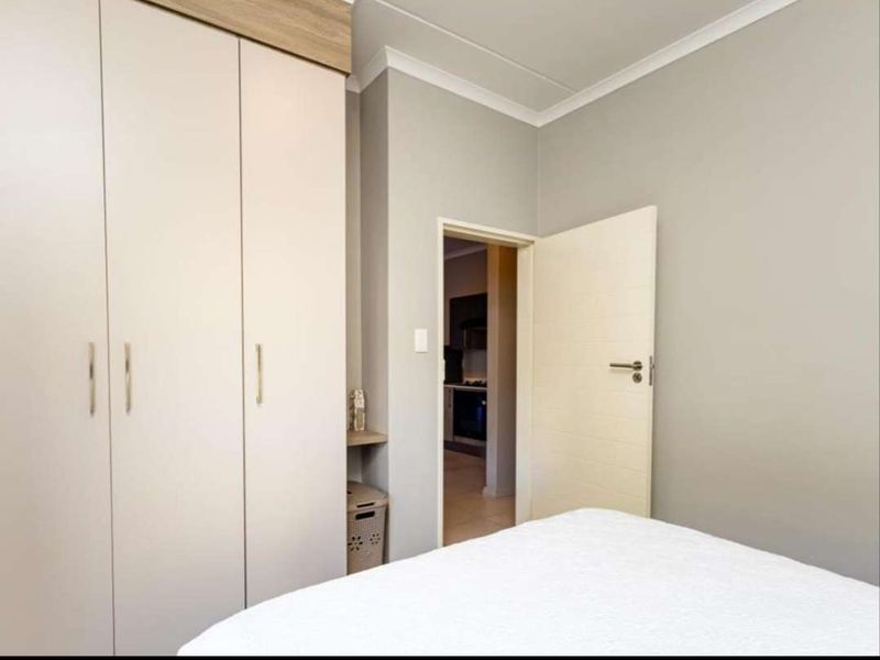 A well-maintained bedroom featuring neutral wall tones and a large built-in wardrobe with integrated storage.