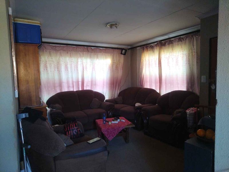 A living room space featuring standard window treatments and basic wall finishes, requiring cosmetic updates to improve the overall aesthetic and condition.