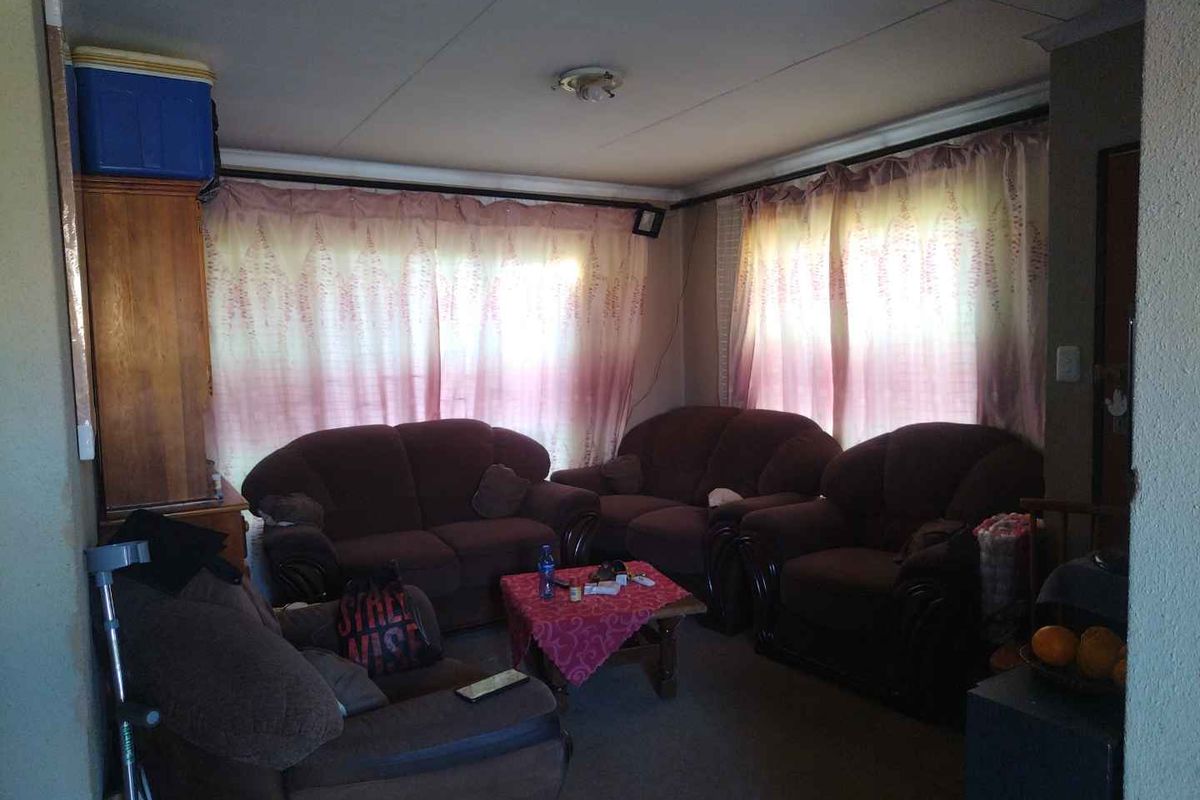 A living room space featuring standard window treatments and basic wall finishes, requiring cosmetic updates to improve the overall aesthetic and condition.