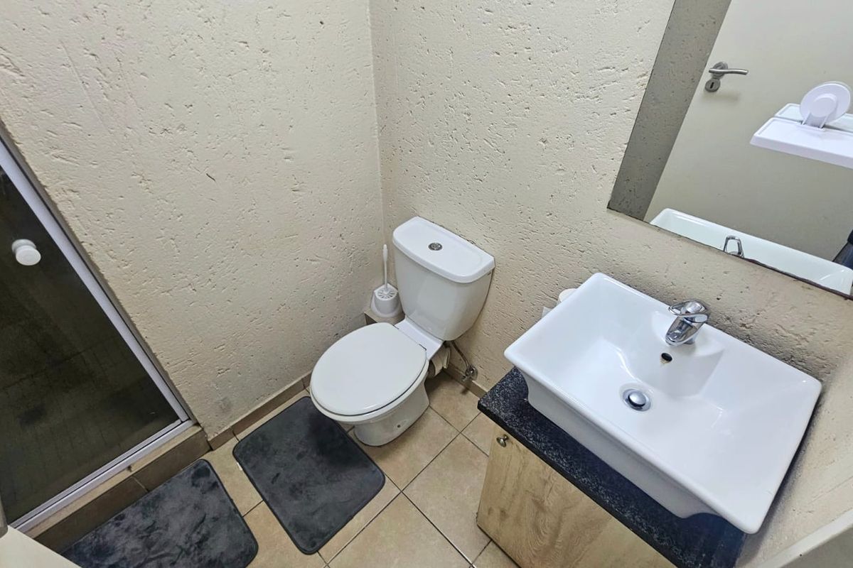 Compact bathroom featuring a modern vessel sink on a vanity, a standard toilet, and a shower enclosure with textured wall finishes.