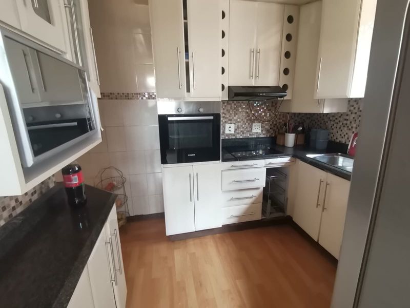 A functional kitchen featuring built-in cabinetry, granite countertops, a tiled backsplash, and integrated appliances including an oven and extractor fan.