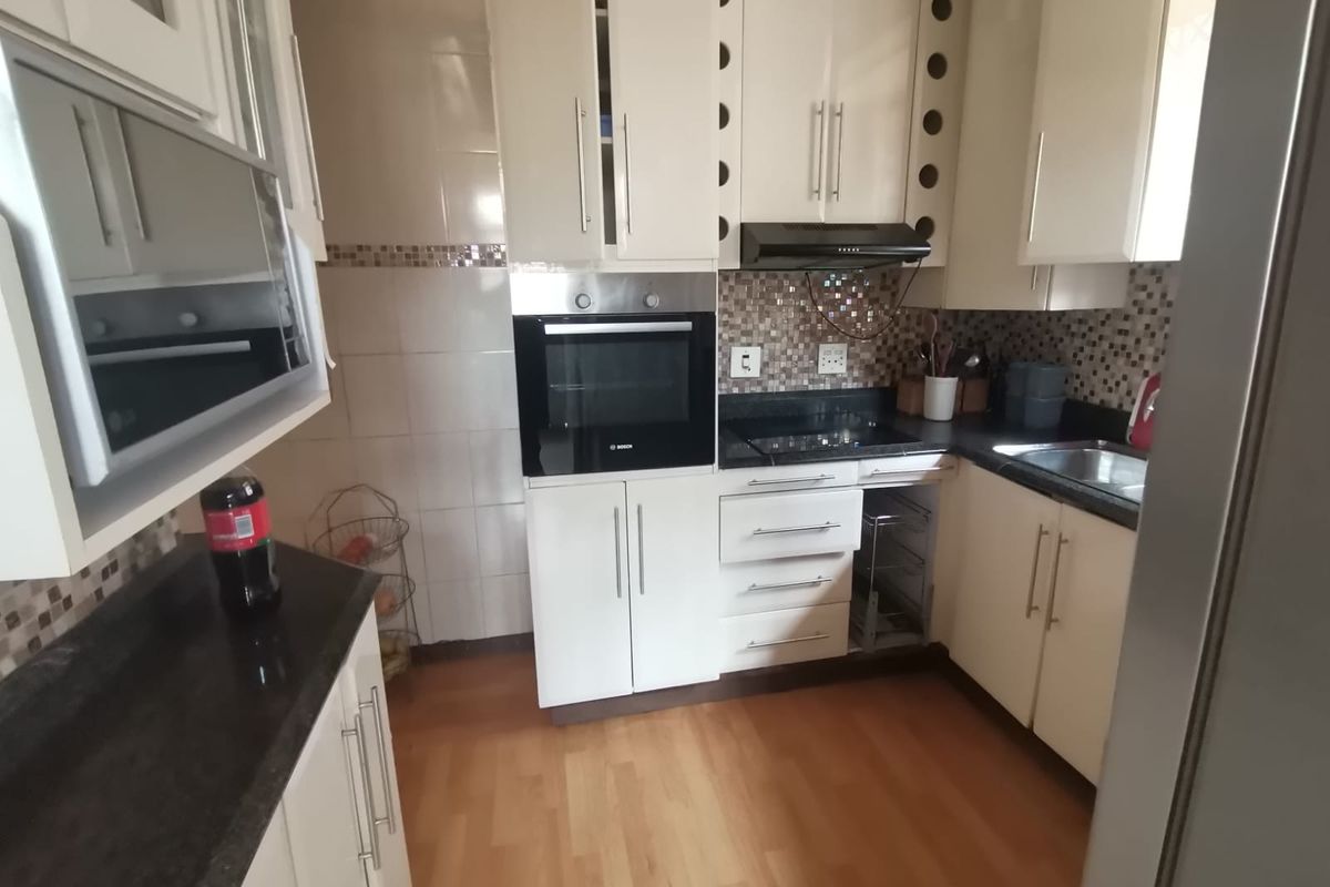 A functional kitchen featuring built-in cabinetry, granite countertops, a tiled backsplash, and integrated appliances including an oven and extractor fan.