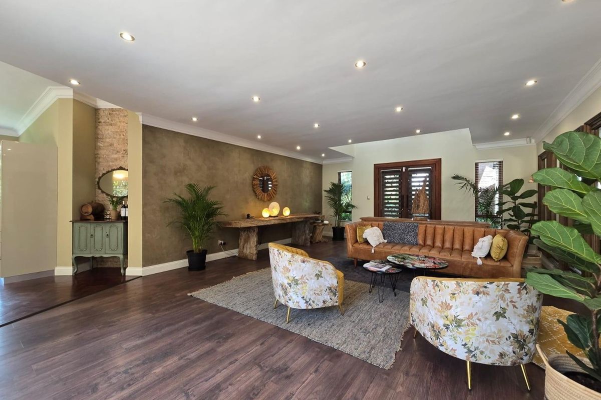 Spacious living room featuring dark laminate flooring, recessed downlighting, and an exposed brick feature wall, creating a warm and inviting atmosphere.