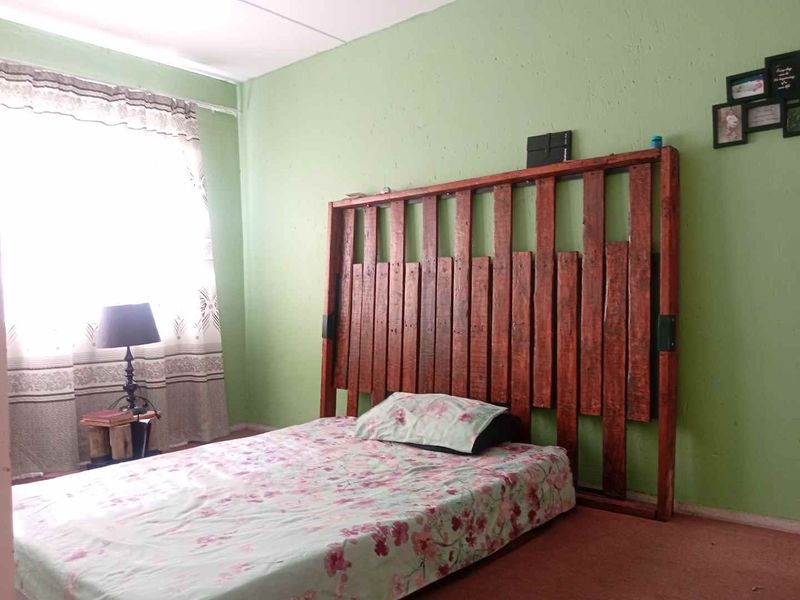 A bedroom featuring green painted walls and carpeted flooring, providing a functional space ready for cosmetic updates.