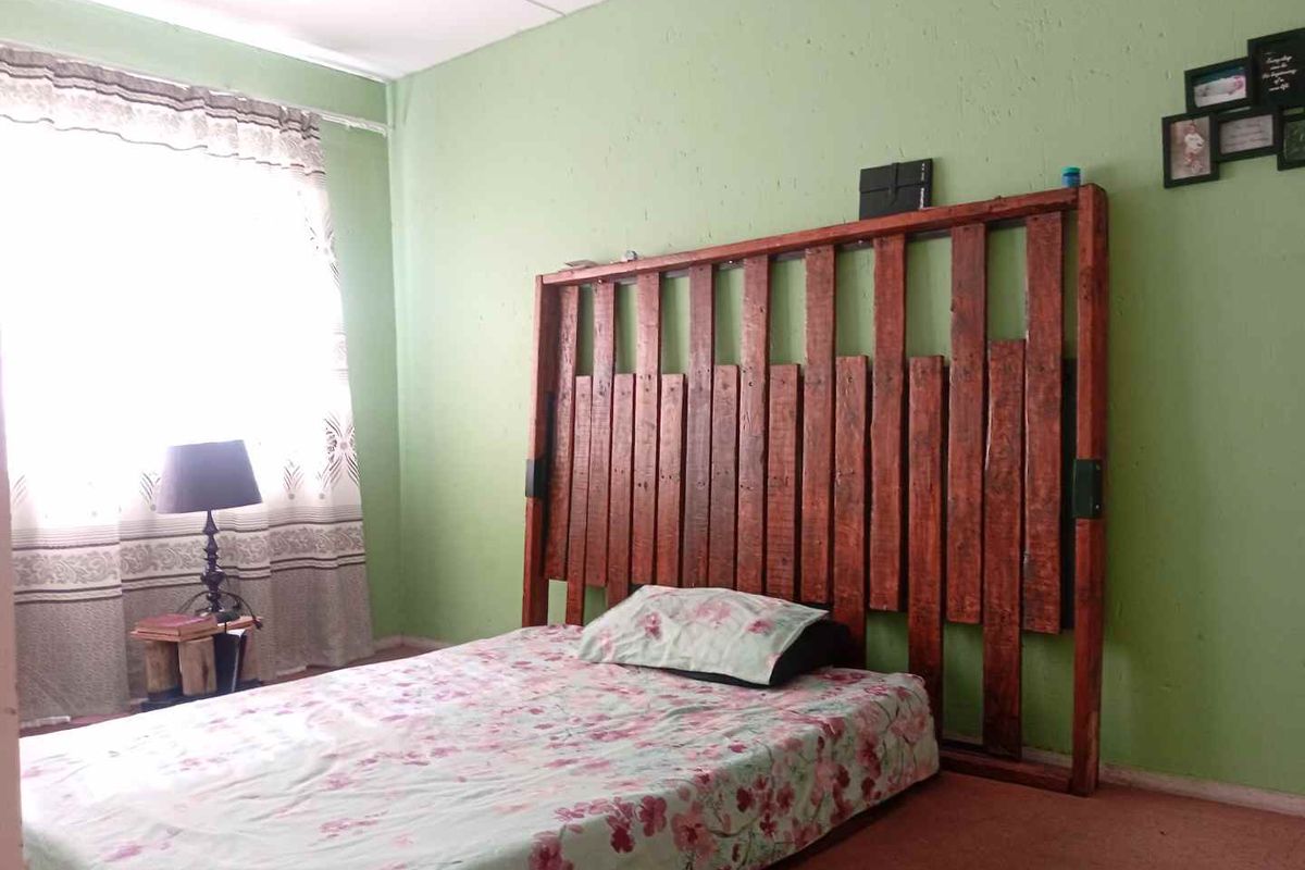 A bedroom featuring green painted walls and carpeted flooring, providing a functional space ready for cosmetic updates.