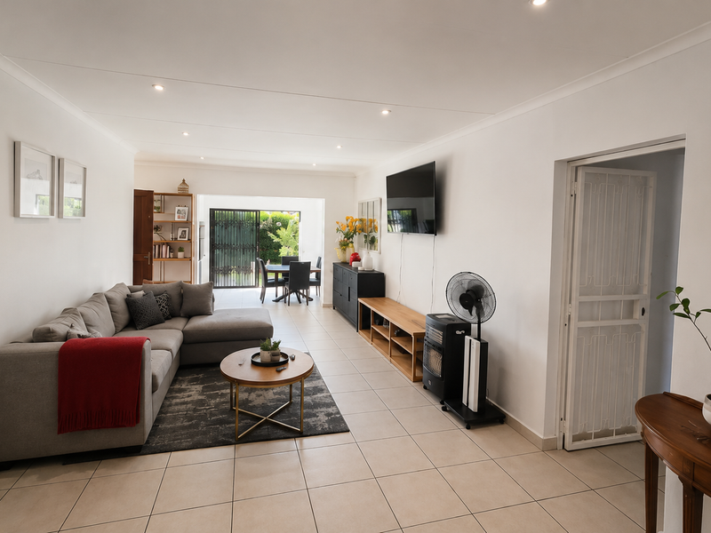 Spacious open-plan living and dining area featuring neutral tiled flooring, recessed lighting, and direct access to the outdoor patio through sliding glass doors.