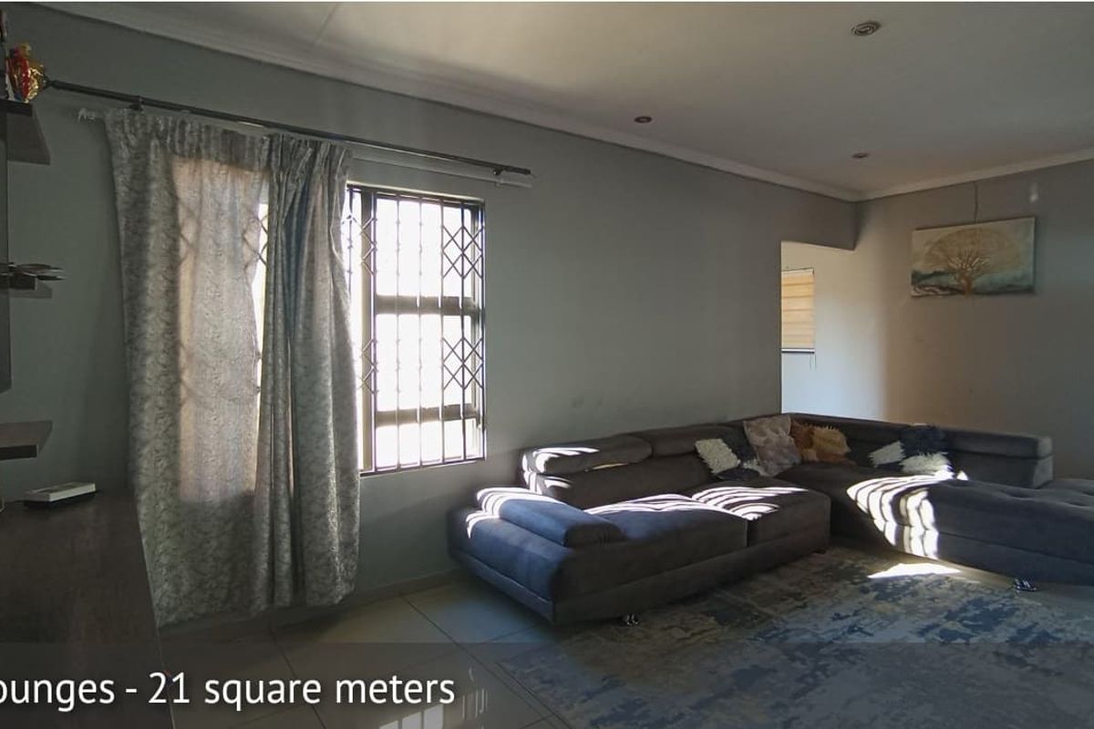 Spacious living room featuring tiled flooring, recessed ceiling lighting, and large windows with integrated security bars.