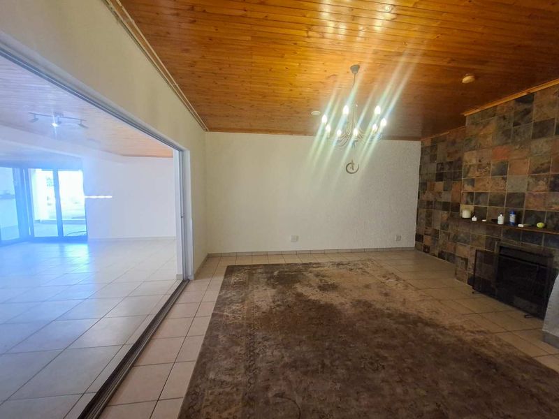Spacious living room featuring a timber ceiling, slate-tiled fireplace, and large sliding glass doors leading to an adjacent room.